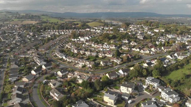 Residential streets in town, surrounded by green fields & countryside, forward moving drone shot