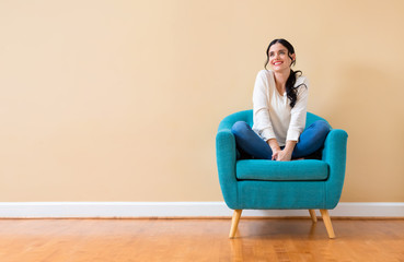 Obraz premium Young woman in a thoughtful pose sitting in a chair