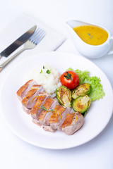 Grilled duck with mashed cauliflower, fried brussels sprouts and orange sauce on a white plate. Close-up.