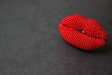 lip-shaped bead brooch on black background