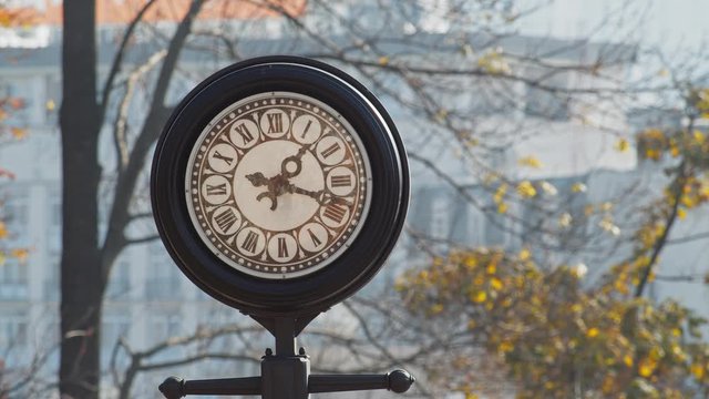 The old vintage round clock with black frame on the street in the grey city background. Lunch time, travel, deadline, history, minute measure concept