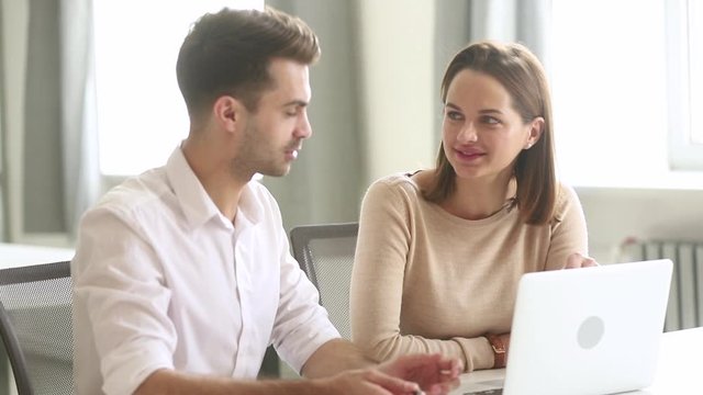 Company members discuss common task sitting near laptop in workplace