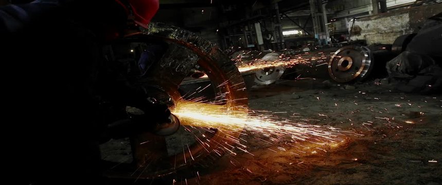 Male hand cuts off pieces of water pipe with angle grinder. Cutting of a steel with splashes of sparks at construction site. Sparks during cutting of metal angle grinder