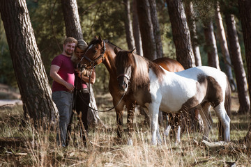P&auml;rchen steht mit ihren Ponys kuschelnd im Wald