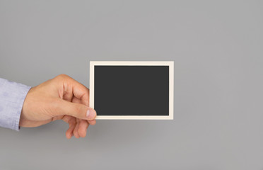 hand holding photo frame grey background