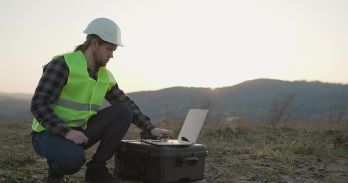 Industrial Engineer in Hard Hat Wearing Safety Jacket Uses Touchscreen Laptop. He Works at the Heavy Industry Manufacturing Factory.