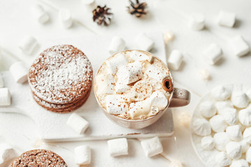 Christmas cookies, milk, cocoa, marshmallows, meringue on a white plate by the window