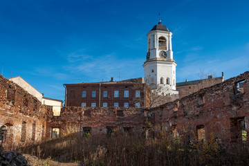 Fototapeta na wymiar View of The ancient clock tower in the city of Vyborg Russia through the ruins of an temple