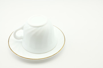 Photo of an empty white cup with a plate on a light background. The concept of lunch, breakfast.