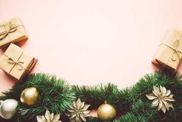 Christmas composition. Fir tree branches, gift boxes, shiny balls on pastel pink background. Flat lay, top view, copy space.