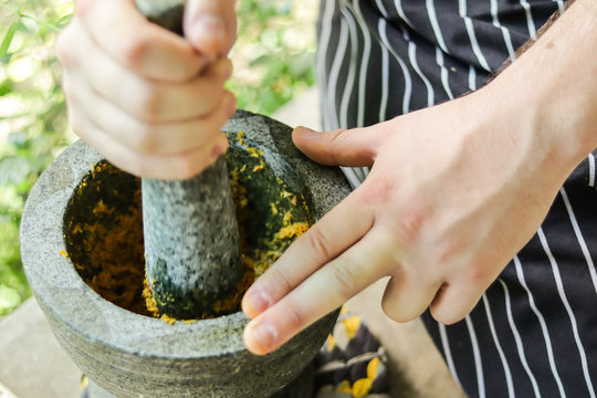 blur, hands, pounding curry paste in rock mortar