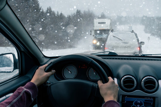 A man drives a car on a winter road in a blizzard
