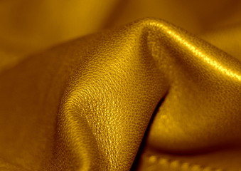 Natural leather texture. Brown background. Golden skin. Yellow shade of material.