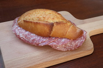 sandwich with salami and wooden cutting board