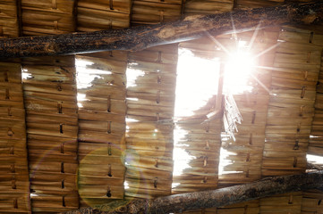 Thatched roof,low angle view..Close up of grunge palm thatch pieces in a row with sunray and flare shining through.