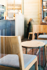 Close-up wooden chairs and empty low table inside cafe. Warm and cozy atmosphere.