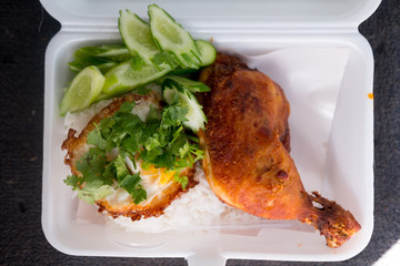 Fried chicken thigh with fried egg on rice in from box
