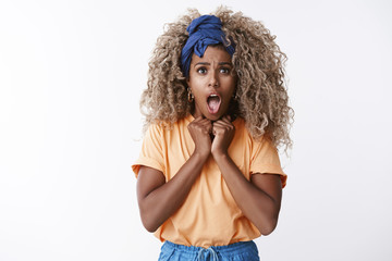Shocked timid and innocent cute, hipster african-american female with blond afro hair, orange t-shirt gasping shocked and scared, open mouth, press hands to chest intense, looking worried