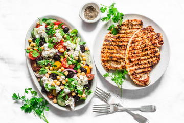 Mediterranean style lunch table - Greek chickpeas salad and pork chops on light background, top view