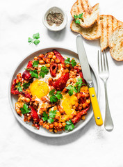 Shakshuka with baked sweet peppers and chickpeas on a light background, top view