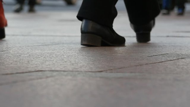 Feet of people walking on a city street. Slow motion