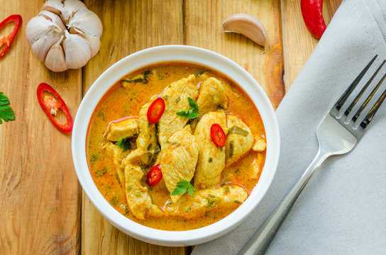 Spicy Chicken Breast In Yellow Curry Sauce With Garlic And Chili  Pepper With Boiled Rice In A Bowl On A Dark Wooden Background.