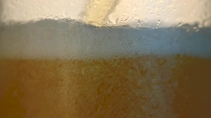 close-up of light beer is poured into a mug with drops