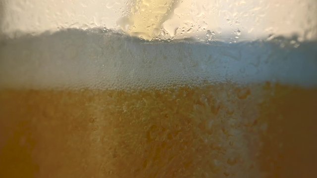 close-up of light beer is poured into a mug with drops