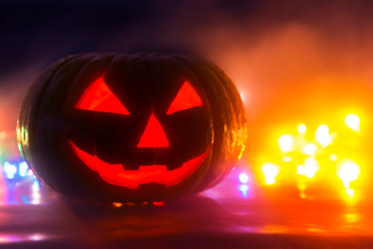 traditional sinister pumpkin head with cut out eyes, mouth, nose on a black background with luminous eyes and a background, a blank for helluin