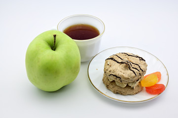 Photo on a white background apple, cake, cup with tea on a saucer. The concept of a delicious breakfast, lunch, healthy food.