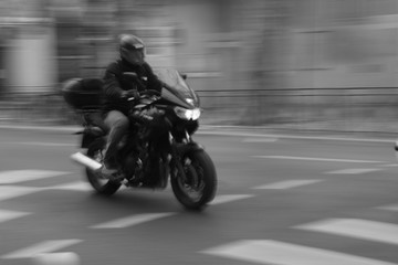 Homme à moto en ville roulant vite