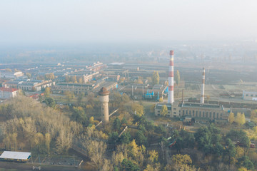 Industrial area of the city with moderate air pollution. Aerial photo from the drone. Chimneys of factories, warehouses, rails.
