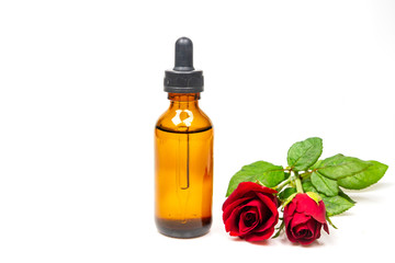 Rose oil in bottle and rose flower isolated on white background. Essential oil product concept.