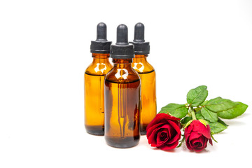 Rose oil in bottle and rose flower isolated on white background. Essential oil product concept.