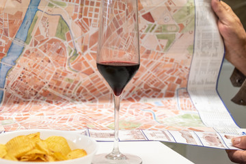Copa de vino con mapa de ciudad en manos de hombre  tomando aperitivo planificando viaje 