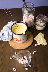 Zubereitung von heißer weiße Schokolade im Milchtopf mit Kakao Pulver und Marshmallows in Küche...
