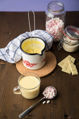Zubereitung von heißer weiße Schokolade im Milchtopf mit Kakao Pulver und Marshmallows in Küche...