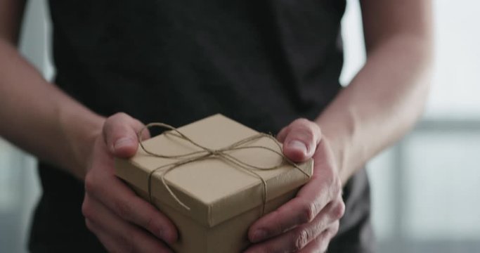 Slow motion young man shows brown craft paper gift box