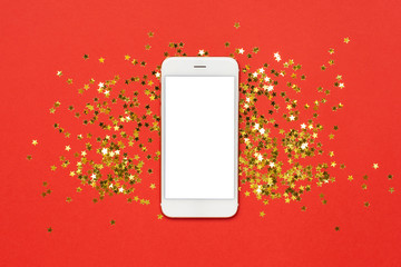 Mobile phone with golden stars confetti on red color paper background