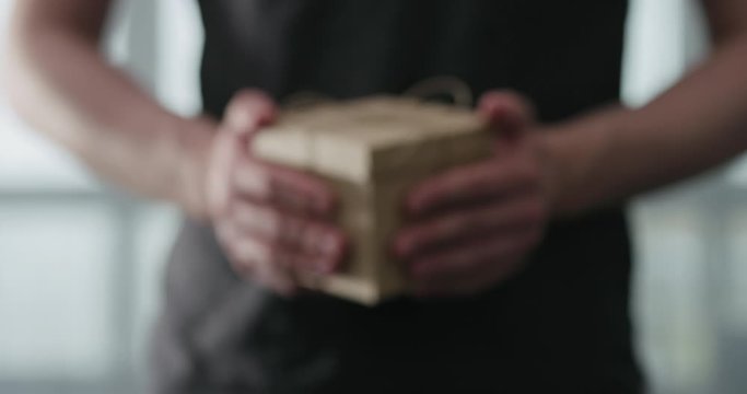Slow motion young man shows brown craft paper gift box