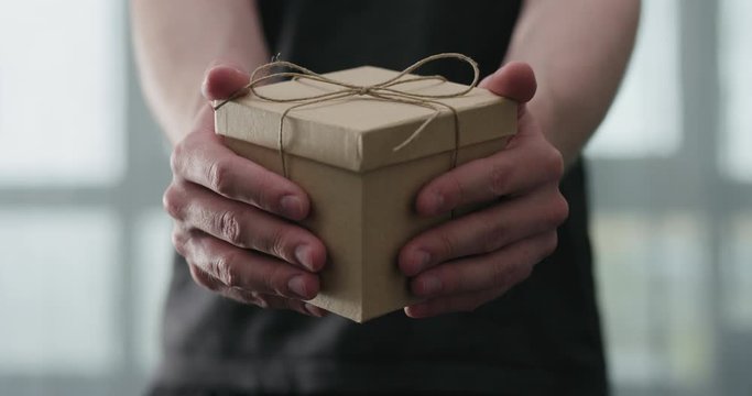 Slow motion young man shows brown craft paper gift box