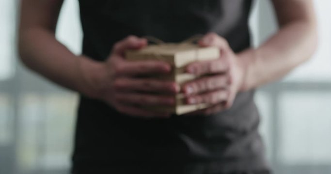 Slow motion young man shows brown craft paper gift box
