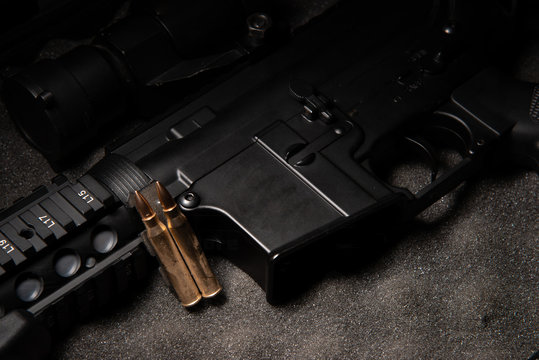 dark assault rifle on dark grey foam with brass bullet ammo ready to fire stock photo