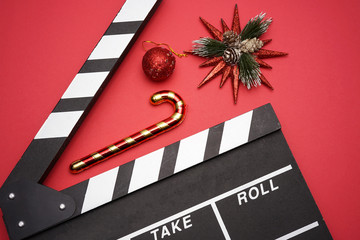 Filmmaker clapperboard with christmas decorations on red background. A Christmas movies and holiday...