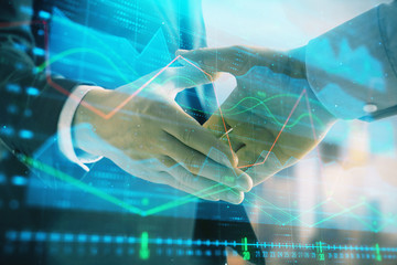 Double exposure of financial graph on cityscape background with two businessman handshake. Concept of stock market deal