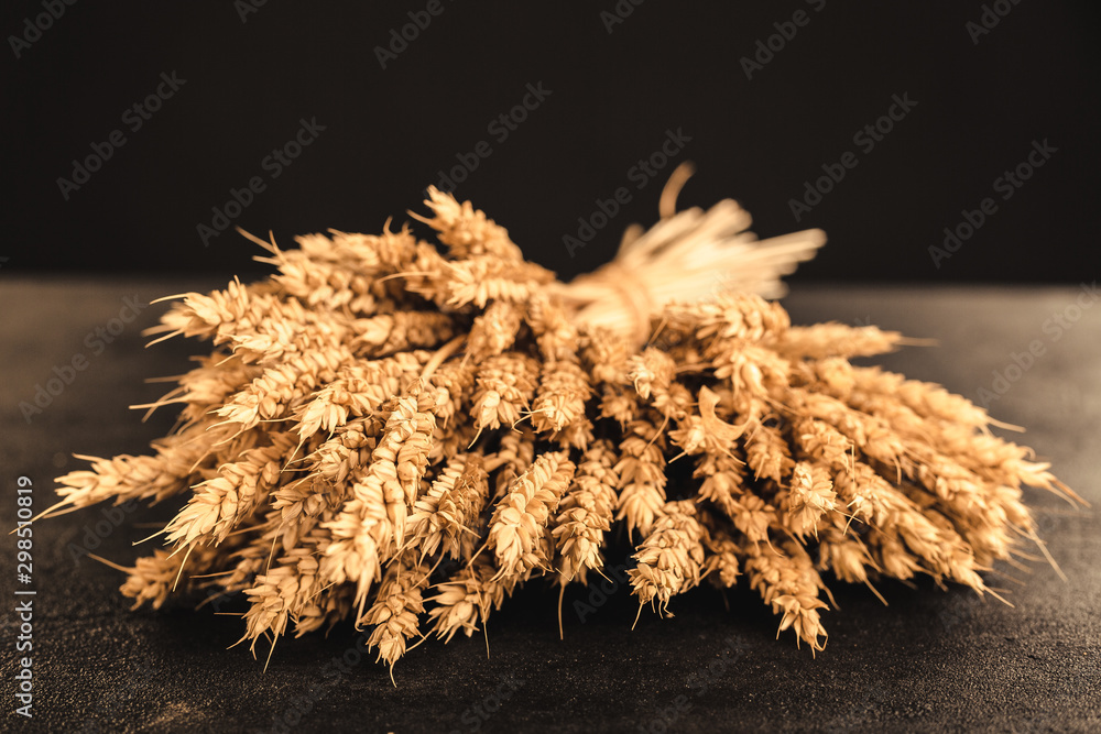 Wall mural ears of wheat and grains on dark stone background