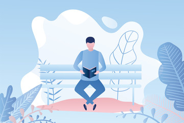 Handsome man reading a book or magazine while sitting on a bench