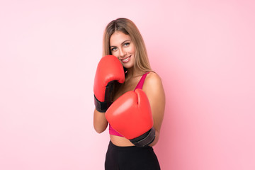 Young sport blonde woman with boxing gloves over isolated pink background