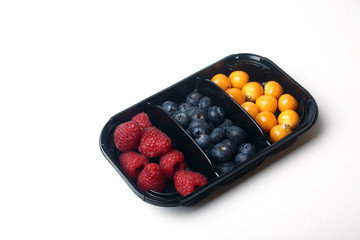 plastic plate with cape gooseberry, strawberry and blueberry isolated on white background