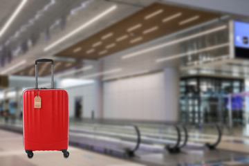 Red suitcase with TRAVEL INSURANCE label in airport terminal